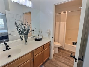 Rinse off the sand and salt in the spacious bathroom, featuring a roomy vanity and a relaxing tub/shower combo—perfect for unwinding after a sun-soaked day at the beach!