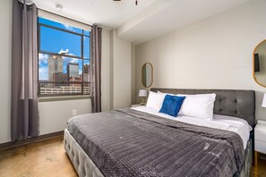 Elegant bedroom featuring a king-size bed, plush linens, and large windows.