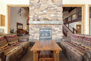 Access a cozy common room with a grand stone fireplace, rustic sofas, and open layout—perfect for relaxing, gathering, or warming up after mountain fun.