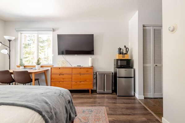 Cozy bed with rave reviews, forest views, desk with natural light, smart TV, and kitchenette—perfect for peaceful workdays and relaxing nights.