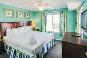 This inviting master bedroom features a serene coastal color palette, a spacious king-sized bed, and ample natural light, perfect for family relaxation.