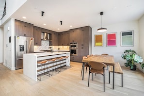 A modern kitchen-dining area with stainless steel, artistic touches, and soft, elegant lighting.