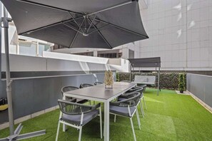 A large balcony with astro turf, setting and a swing set.