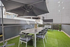 A large balcony with astro turf, setting and a swing set.
