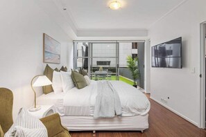 The master bedroom with a king sized bed, balcony & 50 inch smart tv.