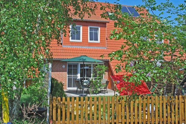 Komplett umzäunter grün gewachsener Garten mit Terrasse.