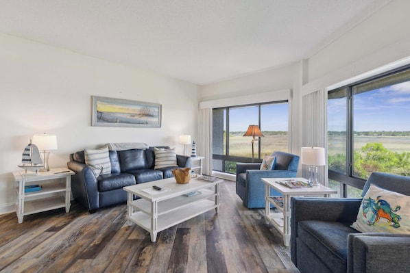 Bright living area with ample seating, balcony and TV