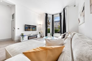 Unwind in the sun-drenched lounge with a smart TV, modern fireplace, and peaceful garden views