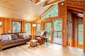 Cozy living room with direct access to the balcony and forest views