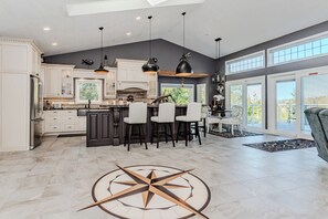 Chef-style kitchen with island seating and forest views—ideal for cooking, gathering, and enjoying your stay. A bright, open vacation rental with all the comforts of home.