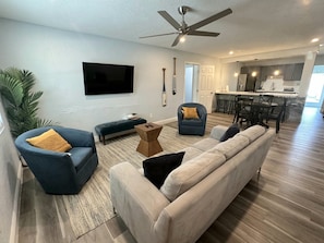 Modern open-concept living room with smart TV, contemporary furnishings, and seamless flow to the kitchen and dining area.