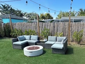 Spacious turfed backyard with cozy outdoor seating, a fire pit, string lights, and full fencing—perfect for relaxing evenings. Pet-friendly and ideal for families!