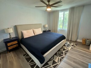 Spacious primary bedroom with a plush king bed, modern decor, and natural light pouring through large windows.