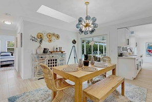 This eclectic dining room blends natural textures with artistic flair—featuring a rustic wood table, woven chairs, and statement lighting under airy skylights. Perfect for casual meals or stylish entertaining.