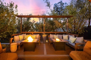Relax around dual firepits in a cozy outdoor lounge, perfect for evening gatherings.