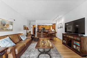 Living area with a large flat-screen TV, beautiful stone fireplace, queen sleeper sofa, and balcony access.