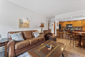 Living area with a large flat-screen TV, beautiful stone fireplace, queen sleeper sofa, and balcony access.
