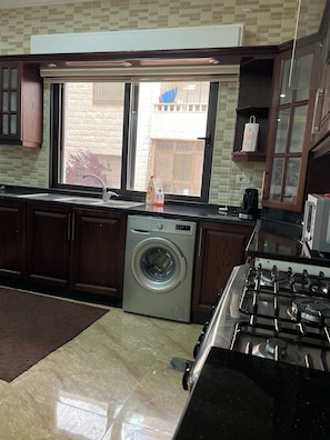 well equipped kitchen with washing machine, gas stove, fridge, microwave, kettle