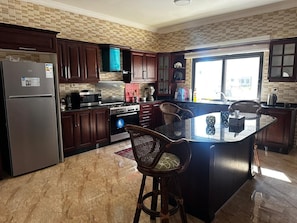 full well equipped kitchen with island and adjacent family den with TV