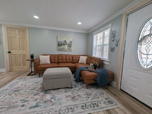 Enter into the livingroom space with sectional couch, and hall tree for coats