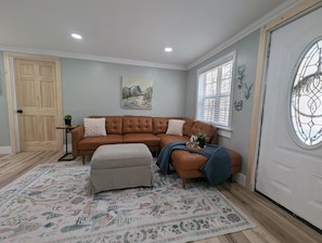 Enter into the livingroom space with sectional couch, and hall tree for coats