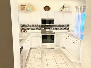 Huge open kitchen w/quartz, stainless, breakfast bar, bright sunny windows
