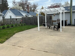Backyard space with charcoal grill, firepit, and pergola