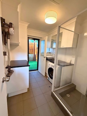 Bathroom with step in shower and washing machine/dryer.