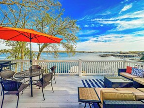Imagine relaxing on this expansive deck overlooking the sparkling water, perfect for entertaining guests or enjoying peaceful moments. This stunning outdoor space offers ample seating, an umbrella for shade, and breathtaking waterfront views, making it an ideal extension of your living area.