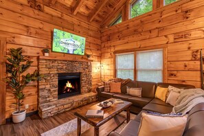 Unwind in rustic luxury – this warm and inviting living room features a stone fireplace, plush sectional seating, and soaring wood-paneled ceilings, perfect for relaxing after a day in the Smoky Mountains.