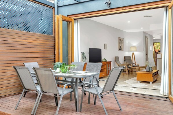 Beneath a transparent roof, the outdoor dining area comfortably seats six—ideal for lingering over a relaxed breakfast or sharing a cosy alfresco dinner with loved ones.
