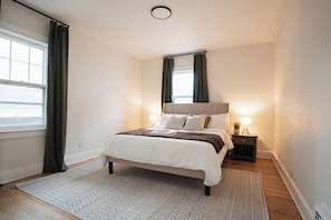 Large, spacious primary bedroom with queen size bed, premium pillows, and linens
