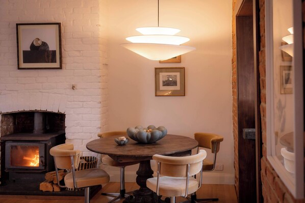 An open plan living and dining space warmed by the fire and scented by the fresh firewood. In Tasmania tradition, a bowl of local walnuts sits on the table.