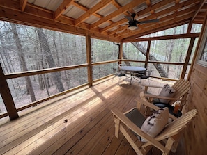 South-facing covered porch, complete with outdoor dining table, Adirondack chairs and ceiling fan