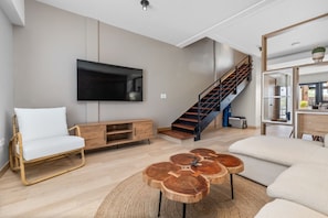 Relax in style! This cozy nook features a comfy chair and a stunning wood coffee table, with a sleek TV for your entertainment. Perfect for winding down!