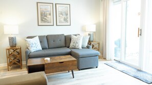 living room - Relax in the cozy living room, featuring a comfortable sofa perfect for unwinding after a day at the beach. Two stylish end tables with soft-glow lamps create a warm, inviting ambiance for evening lounging or reading. Step through the sliding doors to your private back deck—ideal for morning coffee or sunset cocktails with a gentle ocean breeze.