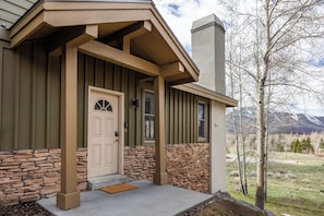 Inviting entryway with rustic wood and stone finishes, opening to peaceful mountain views and tall aspens all around.