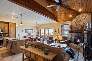 - Gather by the stone fireplace in a warm, lodge inspired living room full of charm
- Vaulted wood ceilings and natural textures set a cozy alpine tone throughout
- Open layout connects kitchen, dining, and lounge, perfect for group getaways