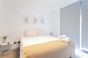 Relax in this bright and cozy bedroom featuring a plush bed and soothing decor, perfect for a restful stay.