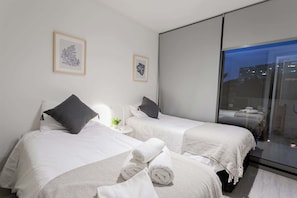 Cozy twin bedroom with city views, perfect for a restful stay. Enjoy modern decor and comfort in this inviting space.