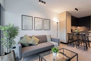 Experience modern comfort in this stylish living space, featuring a cozy sofa, elegant decor, and a welcoming dining area perfect for relaxation.