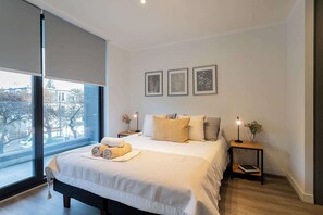 Relax in this serene bedroom with a plush bed, stylish decor, and a view that invites natural light for a perfect retreat.