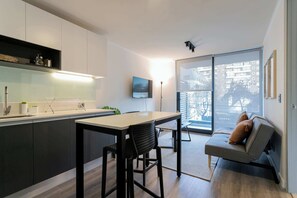 Experience modern living with a sleek kitchen, cozy sofa, and stunning city views from your private balcony.