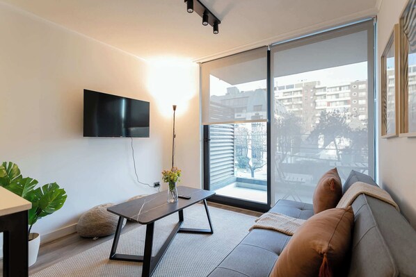 Relax in this modern living room with a cozy sofa, natural light, and a view of the cityscape.