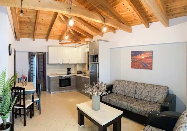 Bright and airy living space featuring natural wood beams, cozy seating, and a fully equipped kitchen