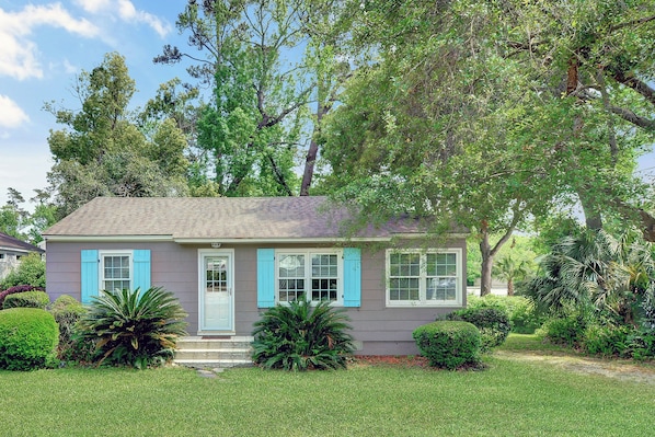 Front Exterior With Coastal Shutters - 204 Ashantilly Avenue makes a bold first impression with bright blue shutters, a wide front yard, and classic St. Simons Island charm—just minutes from the beach.