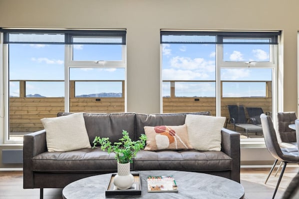 Enjoy breathtaking panoramic views from this modern living room, featuring a comfortable leather sofa, a stylish coffee table, and floor-to-ceiling windows.