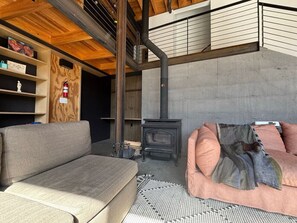 Unwind in this inviting lounge space, featuring a sleek wood-burning stove and lofted design.