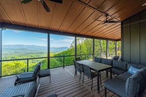 Spacious, covered deck with seating, outdoor dining, and access to a park-style grill