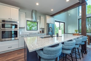 Kitchen with island seating for 4, wet bar, and coffee station with a drip-style coffee maker and Keurig